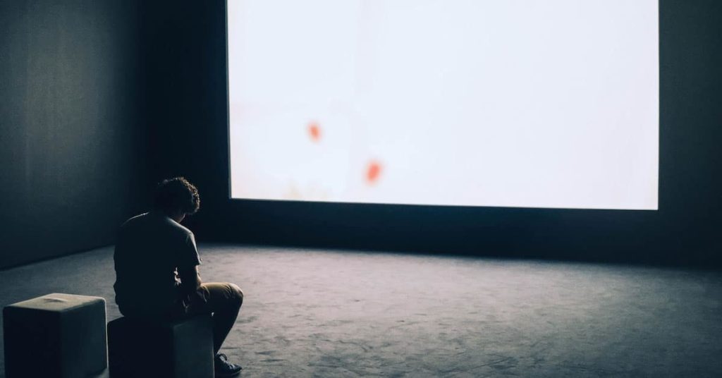 Man Sitting in Front of Turned-on Screen