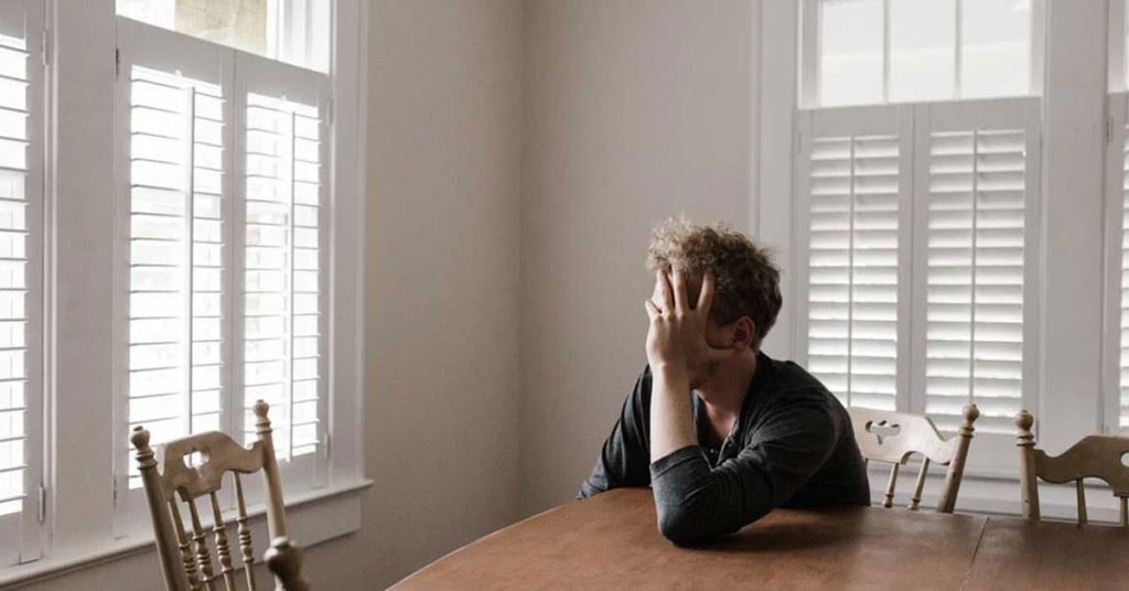 Photo of Man Leaning on Wooden Table