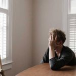 Photo of Man Leaning on Wooden Table