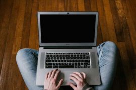 Person in Blue Denim Jeans Sitting on Floor Using Macbook Air