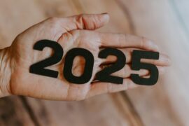 A person's hand holding the number twenty twenty five.