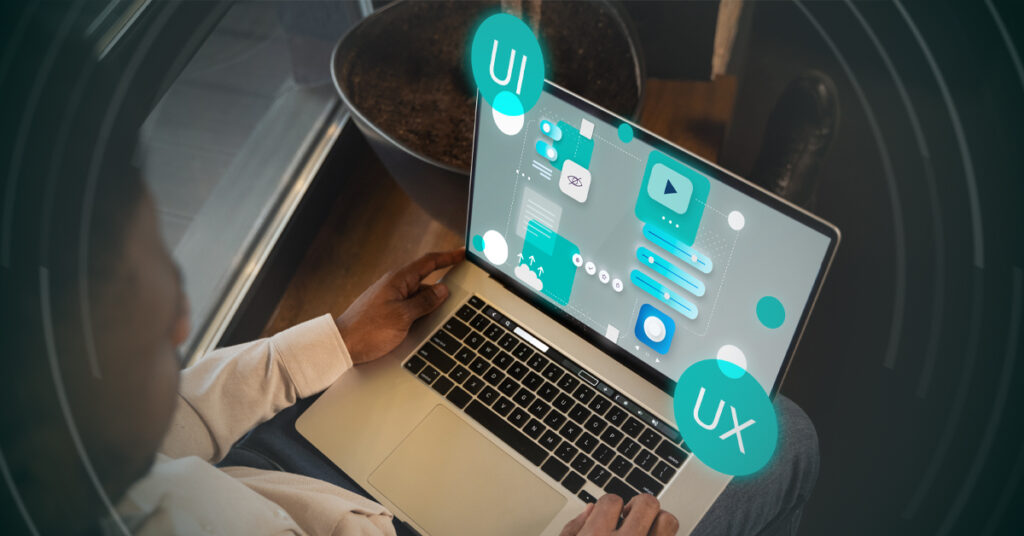A person using a laptop with digital UI and UX interface graphics projected above the screen, illustrating concepts of user interface and user experience design.