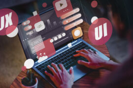 Person using a laptop with digital graphics illustrating UX and UI concepts floating above the screen, including icons, charts, and interface elements.