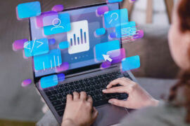 A person using a laptop with illustrated digital icons, including graphs, user avatars, and code, floating above the screen, symbolizing data analysis and technology.